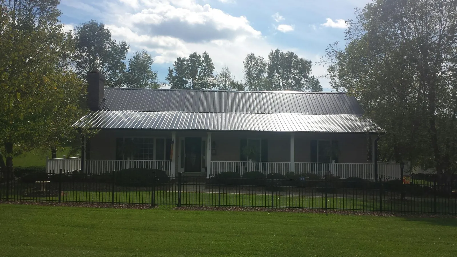 Gray metal roof on a brick ranch with a full width front porch — Gutter Guard Installation work by our crew in Logan